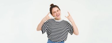 Heyecanlı genç bir kadının portresi eğleniyor, rock 'n roll yapıyor, konserden hoşlanıyor, neşeli poz veriyor, beyaz arka planda duruyor..