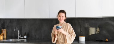 Güzel bir ev hanımı portresi, bornozlu genç bir kadın, elinde bir fincan kahve, mutfakta çay içen, sabahları eğlenen..