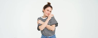 Şefkatli, güzel esmer kız imajı, kendine sarılıyor, özen ve sevgi kavramı, beyaz arka planda duruyor..