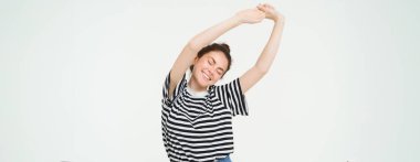 Mutlu genç bir kadının portresi, kollarını uzatıyordu. Güzel bir uykudan sonra gülümsüyordu. Beyaz arka planda duruyordu..