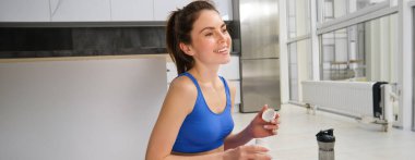 Güzel ve sağlıklı kadın portresi, vitamin almak, kas ve kemikler için beslenme takviyeleri, evde egzersiz yapmak..