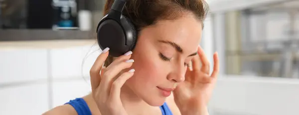 Face of beautiful woman in wireless headphones, enjoys sound, listens to music in wireless headphones.