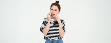 Şok olmuş bir kadın görüntüsü, telefonda konuşurken kafası karışık görünüyor, telefonla konuşan birini dinliyor, beyaz bir geçmişi var..