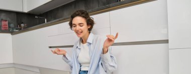 Samimi, gülümseyen genç bir kadın evinde yerde oturuyor, uzaktan çalışıyor, çevrimiçi grup sohbetine bağlanıyor, arkadaşıyla konuşmak için dizüstü bilgisayar kullanıyor..