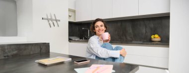 Gülümseyen esmer kadın portresi evde oturur, mutfakta bir fincan çay içer, rahatlar, kapalı havada dinlenmeyi sever. İnsanlar ve yaşam tarzı kavramı