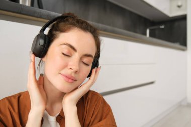 Mutlu, gülümseyen genç bir kadının yakın portresi kablosuz kulaklıkla müzik dinliyor, en sevdiği şarkıyı veya kulaklıkla melodiyi seviyor..