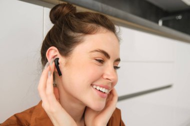 Güzel bir kadının portresi kablosuz siyah kulaklıkla müzik veya podcast dinlemekten, kulaklık kullanmaktan, gülümsemekten ve mutlu görünmekten hoşlanır..