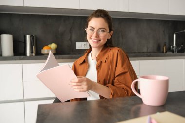Gülümseyen kızın portresi, mutfakta gözlüklü öğrenci, klasörü tutuyor, ödev yapıyor, sınav için düzeltmeler yapıyor, belgeleri okuyor..