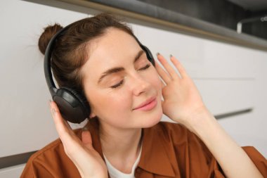 Mutlu, gülümseyen genç bir kadının yakın portresi kablosuz kulaklıkla müzik dinliyor, en sevdiği şarkıyı veya kulaklıkla melodiyi seviyor..