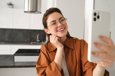 Gözlüklü mutlu bir kadın, selfie çekiyor, akıllı telefondan video kaydediyor, cep telefonu uygulamasında görüntülü konuşmalar yapıyor..