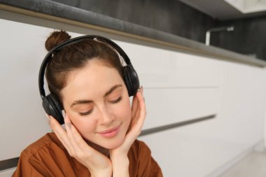 Mutlu, gülümseyen genç bir kadının yakın portresi kablosuz kulaklıkla müzik dinliyor, en sevdiği şarkıyı veya kulaklıkla melodiyi seviyor..