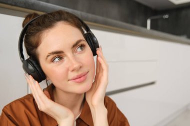 Mutlu, gülümseyen genç bir kadının yakın portresi kablosuz kulaklıkla müzik dinliyor, en sevdiği şarkıyı veya kulaklıkla melodiyi seviyor..