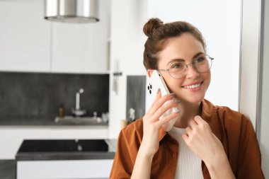 Evde gülümseyen genç bir kadının portresi, cep telefonuyla konuşmak, arkadaşını aramak ve güzel sohbetler yapmak, telefona cevap vermek..