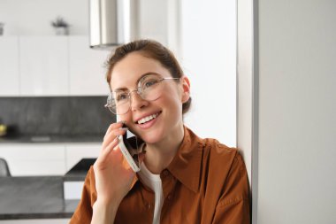 Evde gülümseyen genç bir kadının portresi, cep telefonuyla konuşmak, arkadaşını aramak ve güzel sohbetler yapmak, telefona cevap vermek..