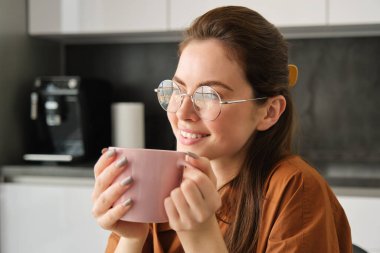 Mutlu kadın portresi, bir fincan kahveyle rahatlamak, başka yere bakmak, pembe kupayla mutfakta oturmak, bitki çayı içmek..