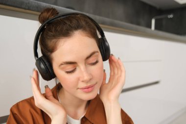 Modern tarz bir kadının kulaklıkla yakın plan fotoğrafını çek, kablosuz kulaklıkla müzik dinlerken rahatla..