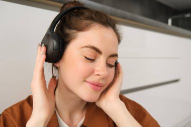 Modern tarz bir kadının kulaklıkla yakın plan fotoğrafını çek, kablosuz kulaklıkla müzik dinlerken rahatla..