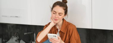Akıllı telefonlu güzel bir genç kadının portresi, cep telefonu uygulaması kullanıyor, telefonda mesaj okuyor ya da haber yayını yapıyor..