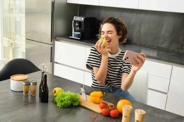 Hayat dolu bir kadın, yemek dünyası blogcusu, video kaydı ya da akıllı telefonuyla yemek yerken selfie çekmesi, elmayı zevkle ısırması. Kamerada yemek pişirmek, taze sebzelerden salata yapmak..