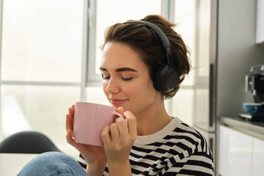Gülümseyen, rahat kadın portresi, sıcak çay içen ve mutfakta müzik ya da e-kitap dinleyen. Yaşam tarzı ve insan kavramı