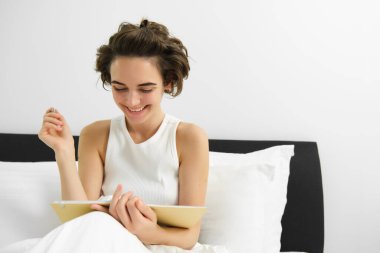 Yatakta günlükle oturan, kalemle günlüğe yazan, defter okuyan, ders çalışan ya da yatak odasından ödev yapan bir kadının portresi. Boşluğu kopyala