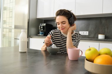 Kahvaltını yapan, elinde kaşık tutan, sütlü mısır gevreği yiyen ve kahve içen bir kadının sabah portresi..