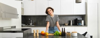 Salata pişiren genç bir kadının portresi. Sevimli kız vejetaryen mutfak tezgahında sebze doğruyor, yemek hazırlıyor..