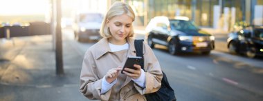 Sokakta cep telefonu kullanan, akıllı telefon ekranına bakan, tebligat okuyan, yol kenarında taksi bekleyen modern bir kadının portresini kapat..