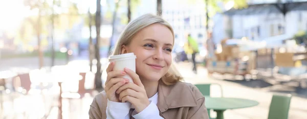 stock image Close up portrait of smiling, happy beautiful European woman, sitting in cafe and enjoying cup of coffee, drinking beverage, enjoying bright sunny day outdoors.