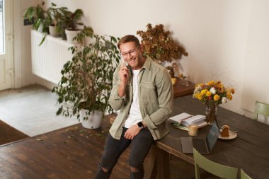 Yakışıklı ofis müdürünün portresi, çalışma alanında çalışan adam, cep telefonuyla konuşan, birini arayan, gülen ve gülümseyen, hoş sohbet yapan, masada oturan..