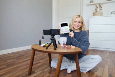Güzel, gülümseyen bir kadının portresi, odasında video kaydı, sehpanın üzerinde kamera, makyajı gözden geçirme, sosyal medya hesabı için vlog hazırlama, özel ders kaydı..