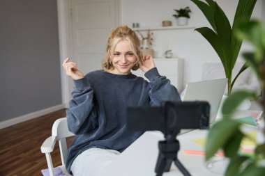 Genç bir kadının portresi, yaşam tarzı blogcusu, hayatı ve günlük hayatı hakkında video kaydı, dizüstü bilgisayarın önünde oturması, takipçilerle konuşması, odasında oturması..