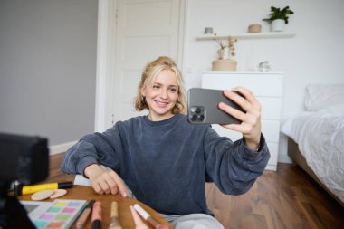 Genç kadın portresi, kız güzellik blogcusu, yatak odasında video kaydı, sosyal medya takipçileri için makyaj dersi, selfie çekmek, cep telefonu uygulamasından canlı yayın.