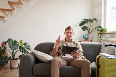 Adam bir dilek diliyor, dijital tablete bakıyor, bavulunu hazırlıyor ve tatile çıkıyor, seyahat acentesinin internet sitesini seçiyor. Boşluğu kopyala