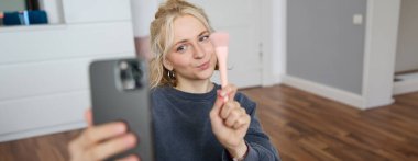 Genç kadın portresi, kız güzellik blogcusu, yatak odasında video kaydı, sosyal medya takipçileri için makyaj dersi, selfie çekmek, cep telefonu uygulamasından canlı yayın.