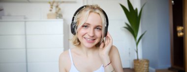 Kablosuz kulaklıklı güzel sarışın kadının portresi, podcast veya en sevdiği şarkıyı dinliyor, yeni kulaklıklarla müzik dinlemekten hoşlanıyor..