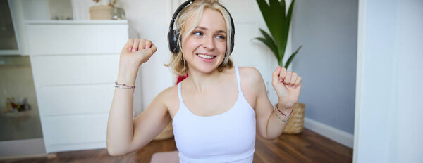 Портрет красивой блондинки, фитнес-женщина танцует в беспроводных наушниках, наслаждаясь тренировкой в любимую песню.
