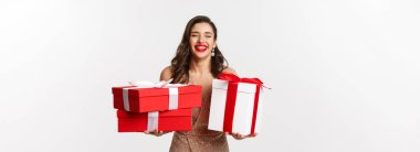 Tatiller, kutlama konsepti. Zarif elbiseli güzel beyaz kadın Noel hediyeleri taşıyor ve gülümsüyor, beyaz arka planda duruyor..