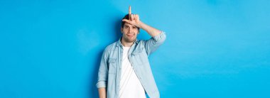 Kaybettiği için alay eden kaba bir adam. Alnında ezik işareti olan ve mavi arka plana karşı duran biri..