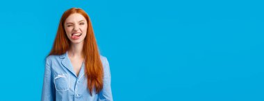 Kaygısız ve komik kızıl saçlı genç kız pijama partisi sırasında uyumak istemiyor. Dilini gösterip aylak aylak dolaşmak, dalga geçmek, neşe içinde göz kırpmak, gece kıyafeti giymek, mavi arka plan..