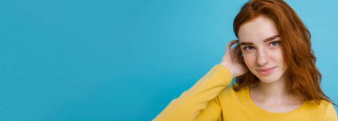 Kameraya gülümseyen kızıl saçlı mutlu kızıl saçlı kızın portresi. Pastel mavi arka plan. Boşluğu Kopyala.