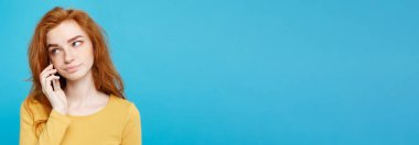 Yaşam tarzı ve teknoloji kavramı - neşeli mutlu Kızıl kızıl saçlı kız arkadaşı ile cep telefonuyla konuşurken şok edici ve stresli ifade ile portresi. Pastel mavi arka plan üzerinde izole