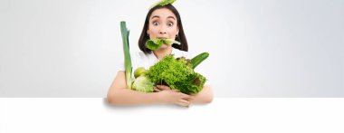 Marul yaprağı yiyen Asyalı kızın portresi. Elinde yeşil orantılı sebzeler var. Sağlıklı bir yaşam sürüyor..