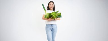 Yeşil diyetteki mutlu genç bir kadının portresi, organik yiyecekler yemeyi seviyor, bahçeden taze sebzeler taşıyor, marul, lahana, beyaz stüdyo geçmişi.