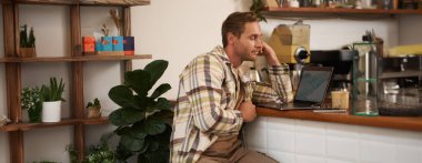 Yetişkin bir adamın bilgisayar ekranına bakması, monitörüne bakması, internette zor işler yapması, kafede oturması, kahve içmesi ve çalışması..