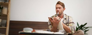 Düşünceli genç bir adamın portresi, tatile çıkan bir turist, tatil listelerini gözden geçiriyor, seyahat etmek istediği şeyleri yazıyor..