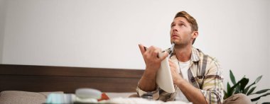 Bavullu bir adamın portresi, tatil için otururken ve eşyalarını toplarken, tatil için eşya listesini kontrol ederken, not alırken, not defterine not alırken. Yaşam tarzı ve turizm konsepti