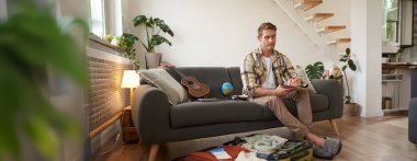 Yolculuk için hazırlanan genç bir adamın portresi, tatile gitmek, bavulun içine giysiler koymak, tatile hazırlanmak..