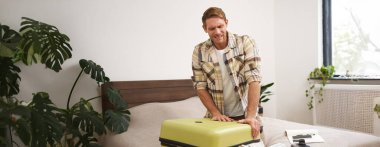 Genç bir yolcunun görüntüsü, bavulunu kapatmaya çalışan bir turist, onu kapatmak için bavulları itiyor, tatilde bir sürü kıyafet taşıyor. Boşluğu kopyala