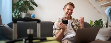 Tatile çıkan adamın portresi, kredi kartına bakmak, internetten bilet almak, web sitesinden otel kiralamak, tatil için hazırlanmak..